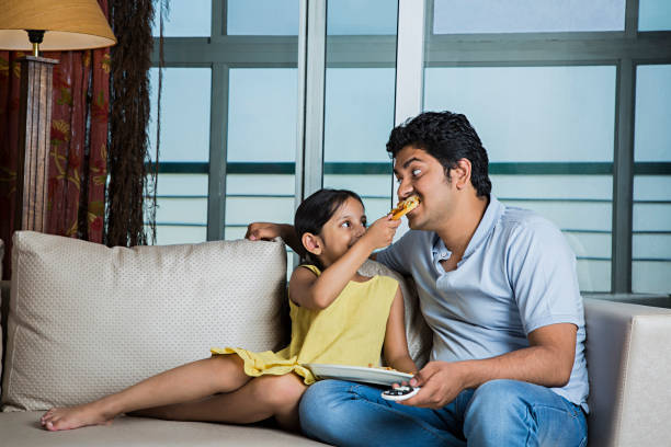 istock Dad and daughter eating cereals on couch - Stock image 1025420120