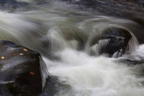 istock Swiftly flowing water across large rocks in a fall landscape 1025424900