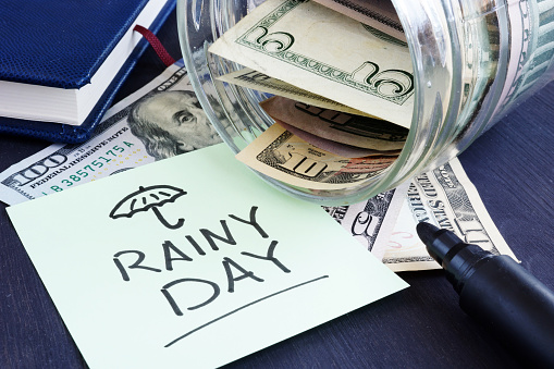 Rainy day fund savings. Jar with dollar bills.
