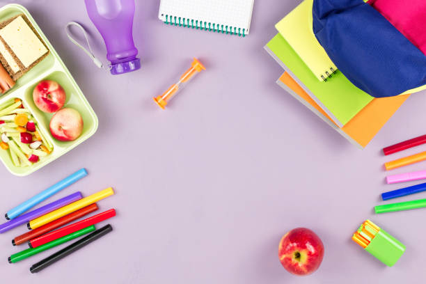 istock School concept flat lay. Kid backpack, lunchbox, water bottle, notebook, markers on wooden desktop 1025426864