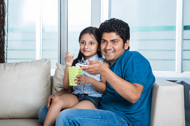 istock Smiling daughter and father watching television - Stock image 1025428626