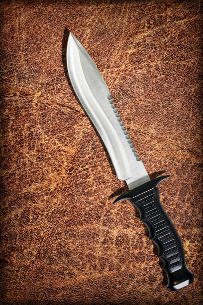 istock Tactical Combat Hunting Survival Sawback Bowie Knife Set On Old Weathered Wizened Cowhide Vignette Grunge Background 1025439042