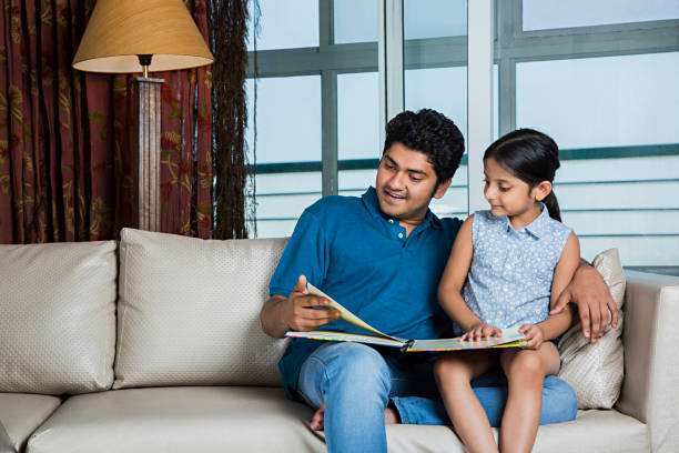 istock Father and daughter are reading books.Sitting on a  sofa. - Stock image 1025444608