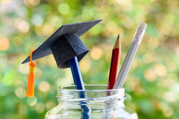Education and knowledge is important for student and most powerful weapon concept : Black graduation cap or hat on pencil in bottle, depicts the power of success in education. Green nature background.