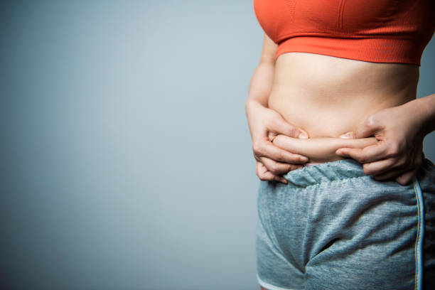 las mujeres pinch una grasa en su abdomen - abdomen humano fotografías e imágenes de stock