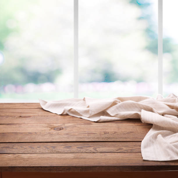 istock Empty wooden deck table with tablecloth near the window in kitchen over bokeh summer background. Kitchen background, product montage display. Mock up . 1025477540