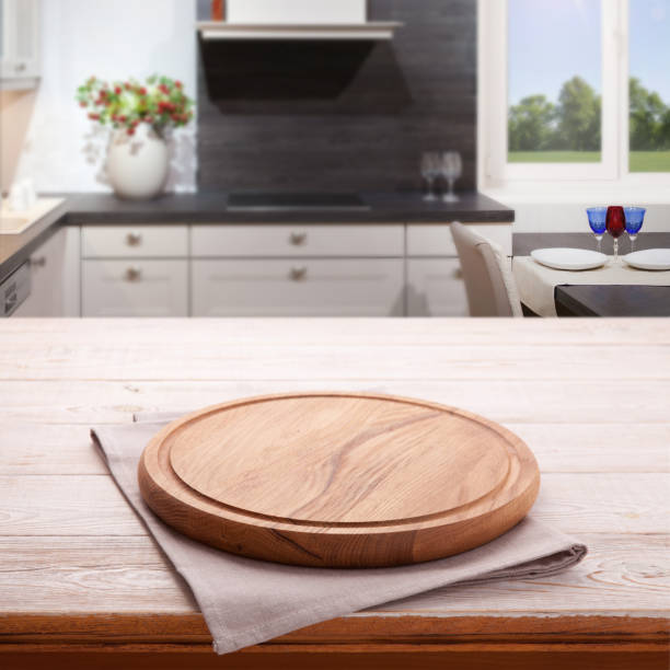 istock Empty wooden table with pizza board and tablecloth near the window in kitchen. White Napkin close up top view mock up. Kitchen rustic background. 1025477620