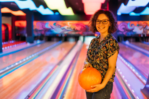 mujer joven jugando bolos - bowling holding bowling ball hobbies fotografías e imágenes de stock