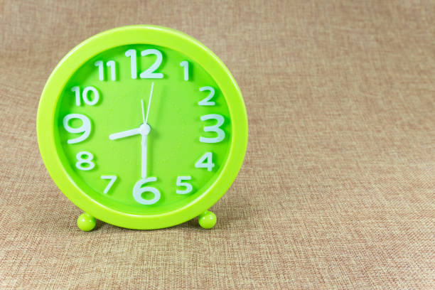 茶色の荒布の背景に緑の目覚まし時計表示半分 8 - 8 oclock ストックフォトと画像