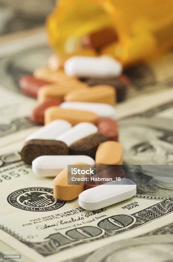 Pills spilled over money  American One Hundred Dollar Bill Stock Photo