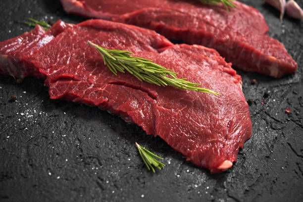 istock Raw ribeye beefsteak with seasonings, black background 1025525916
