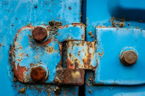 Photo of Door hinge of a blue car rusted nuts abandoned