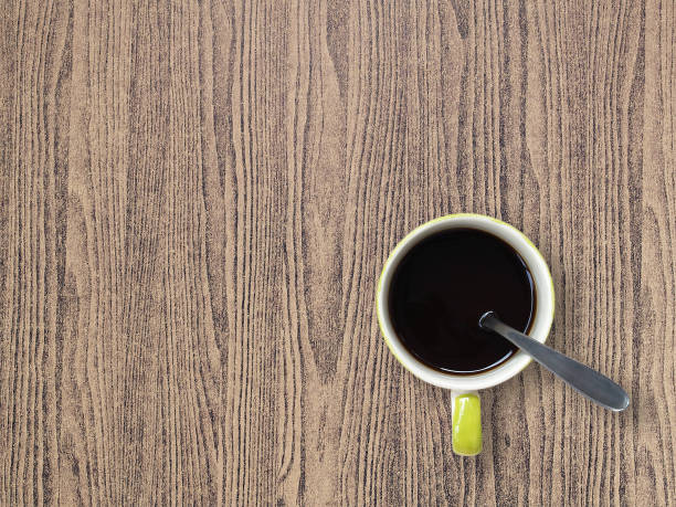 istock small white ceramic coffee cup with black coffee and silver spoon on brown wooden table floor 1025533736