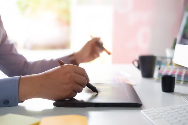 istock Hands of Graphic designer working with digital tablet and mouse pen on table and morning light. 1025536326