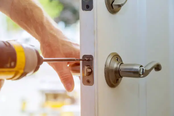Installation locked interior door knobs, close-up wood worker hands install lock.