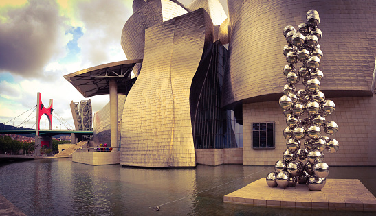 Bilbao, Spain - June 26, 2014: The Guggenheim Museum in Bilbao city with some of its outdoors exhibited works. To the right 'Tall Tree and the Eye' from artist Anish Kapoor