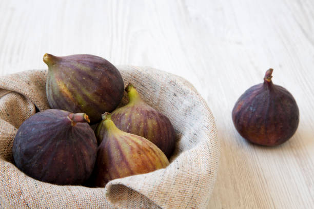 istock Fresh figs in a bowl on a white wooden surface, side view. Close-up. 1025618148