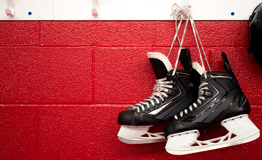 Hockey sobre patines y casco colgando en vestidor con espacio de copia en fondo rojo photo