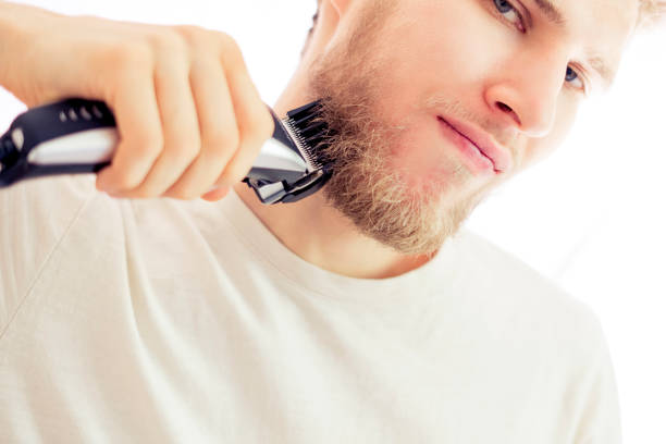 istock isolated young hipster shaving beard with machine on white background 1025666206