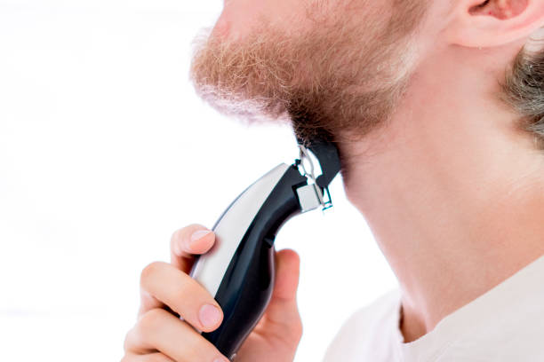 istock close up handsome male shaving his own beard with a machine isolated 1025666208