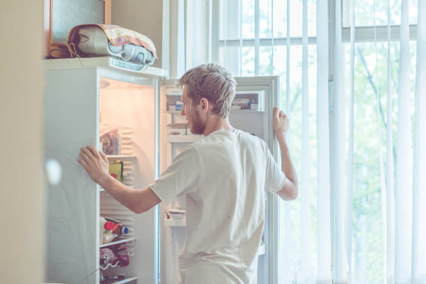 istock young handsome bearded man standing near opended fridge at home kitchen 1025666238