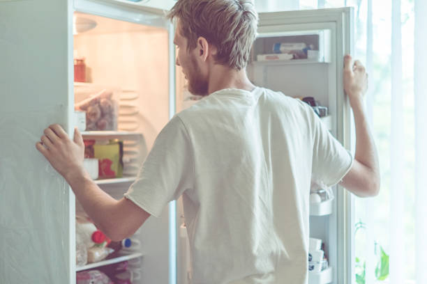 istock young handsome bearded man standing near opended fridge at home kitchen 1025666240