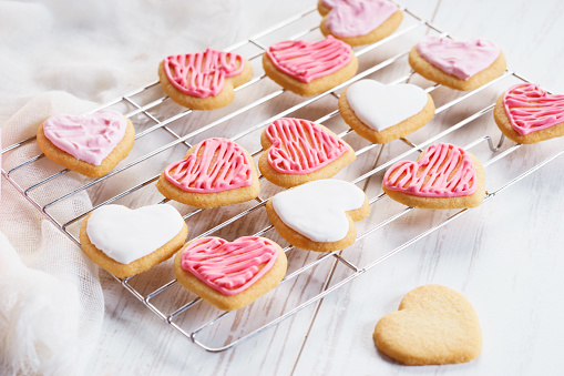 Heart cookies with sweet pink icing on baking rack, love concept.