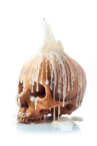 Creepy image of skull with a melting candle on top isolated on white