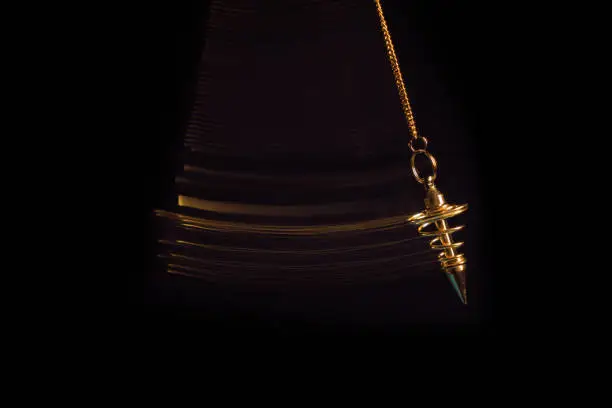 Pendulum used for hypnotism and readings swinging with motion blur