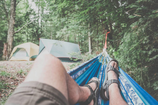 Man relaxing in hammock at summer campsite, Quebec, Canada