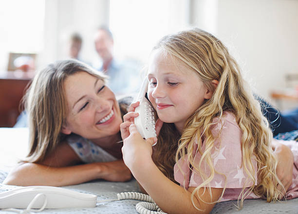 mother and daughter (6-7) talking on telephone - telefono fisso foto e immagini stock