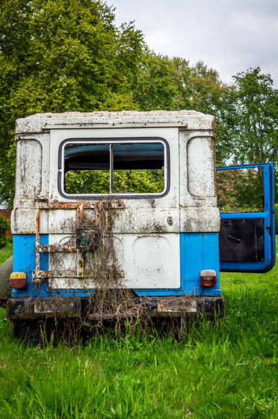 istock Abandoned vintage car blue lush green grass broken glass 1025723366
