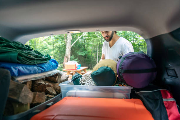 istock Man Unloading the Car trunk packed with luggage and other items for road trip and Camping 1025725644