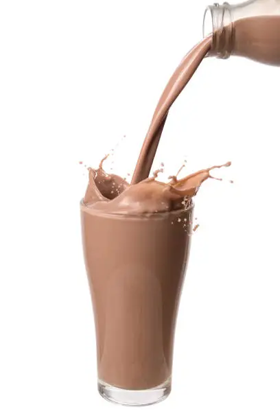 Pouring chocolate milk from bottle into glass with splashing., Isolated on white background.