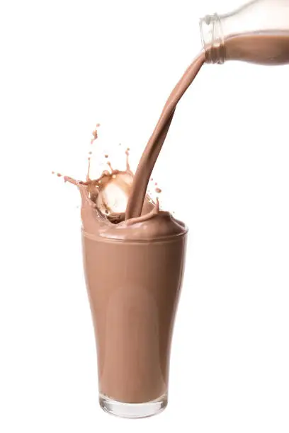 Pouring chocolate milk from bottle into glass with splashing., Isolated on white background.