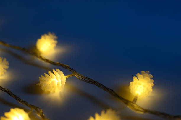 istock Blurred yellow christmas lights in shape of cones in three rows on dark background , low depth of focus. 1025739954