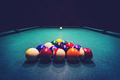 Young woman playing billiards in the dark billiard club.