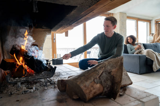 겨울 별장에 그의 파트너와 함께 휴식 하는 동안 로그 벽난로 있는 불타는 남자 - cabin log log cabin winter 뉴스 사진 이미지