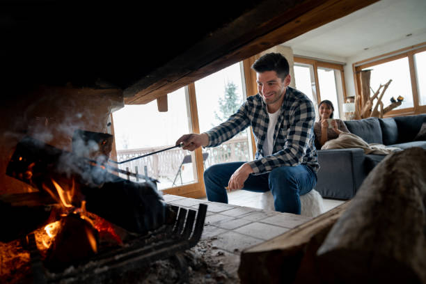 istock Man burning logs in the fireplace while relaxing with his partner at a winter lodge 1025767626