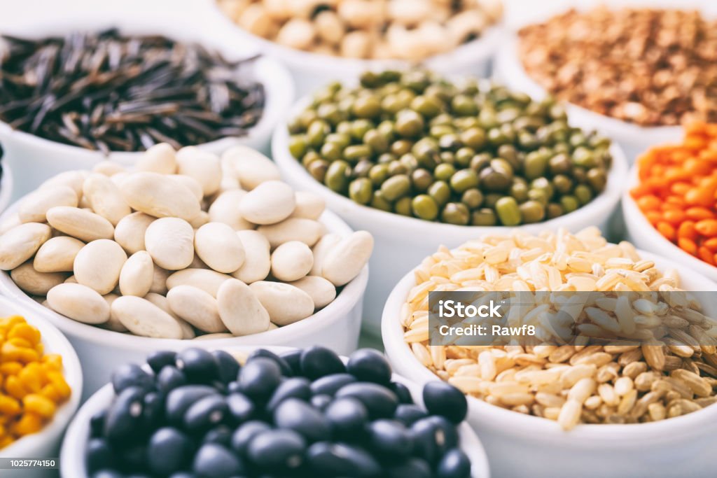 Various raw legumes and rice in bowls Various raw legumes and rice in white bowls Bean Stock Photo