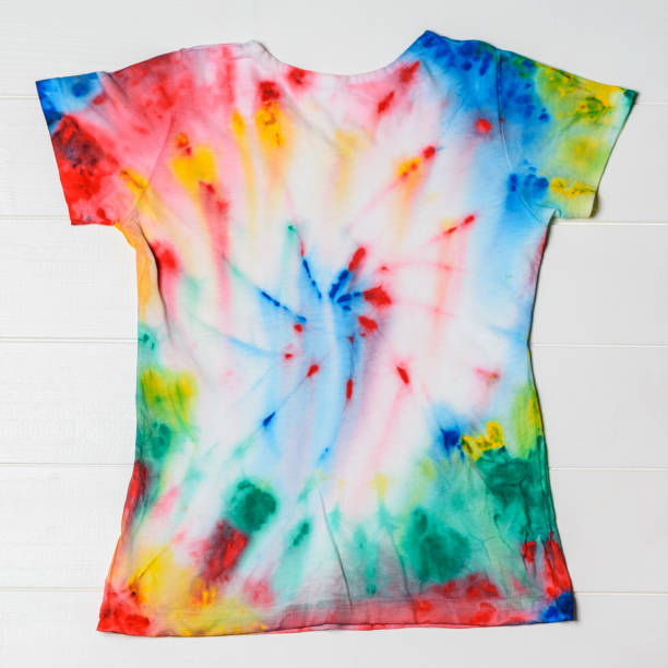 istock White t-shirt hand painted in tie dye style on white table. 1025806816