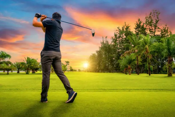 Photo of Man playing golf on a golf course in the sun, Golfers hit sweeping golf course in the summer