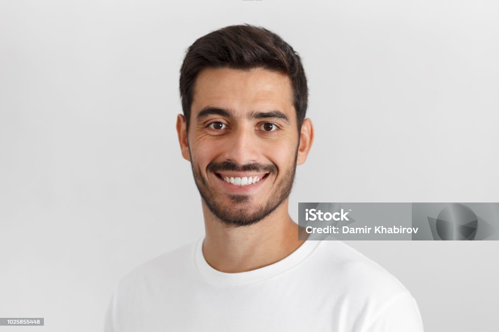 Stylish bearded man with trendy haircut smiling to camera, having pleased expression and cheerful look. Positive emotions concept. Men Stock Photo