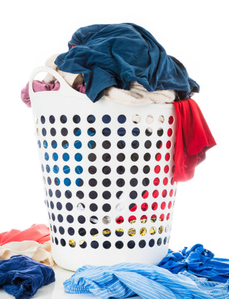 istock Colorful clothes in white laundry plastic clothes basket beside messy stack clothes on floor, Laundry and Housework concept, Isolated on white background. 1025868690