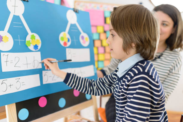 Kid Solving Math Exercises Cute boy solving graphic math exercises at kindergarten, under educator observation montessori education photos stock pictures, royalty-free photos & images