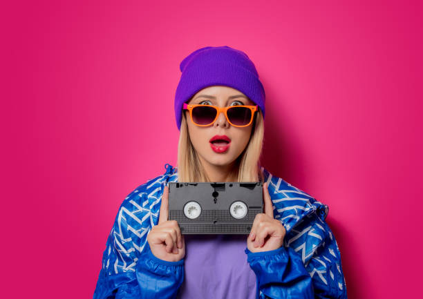 girl in 90s sports jacket and VHS cassette Young blonde girl in 90s sports jacket and VHS cassette on pink background. 1990s style stock pictures, royalty-free photos & images