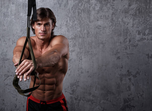 Man during workout with suspension straps Muscular man during workout with suspension straps chest dip on athletic workout stock pictures, royalty-free photos & images