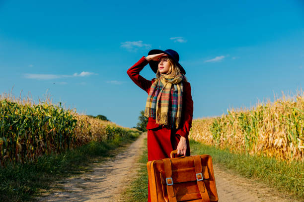 istock girl with suitcase near cornfield 1025907414