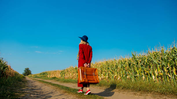 istock girl with suitcase near cornfield 1025907518