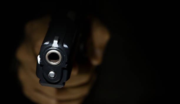 istock male hand holding gun with dark background 1025911318